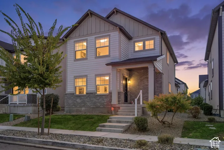 Two-story exterior featuring horizontal lap siding, vertical board-and-batten gable accents, a brick veneer base, and a covered front porch with concrete steps