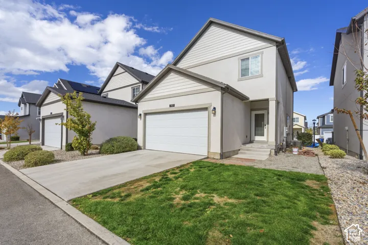 Two-story exterior featuring a light-colored stucco and horizontal siding facade, a concrete driveway, and an attached two-car garage