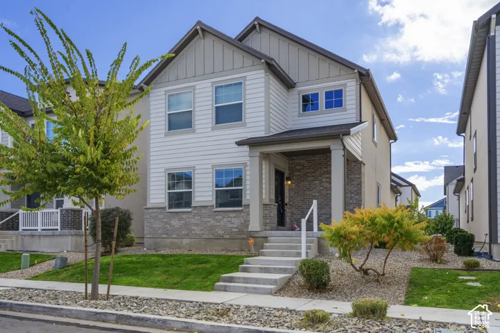Two-story exterior featuring a mix of horizontal lap and vertical board-and-batten siding, stone veneer accents, covered entryway, and asphalt shingle roof