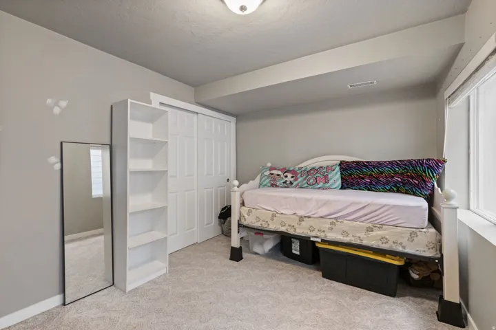 Recessed window with white trim, built-in bi-fold closet doors, wall-mounted light fixture, and soft carpet flooring