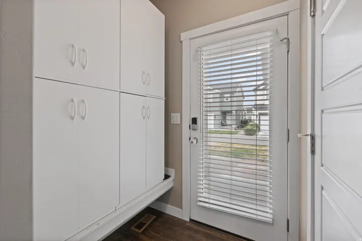 Full-height storage cabinetry, wood-finish flooring, and a white paneled door