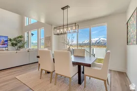 Dining area featuring a contemporary linear chandelier, dark wood-finish table, and light fabric chairs