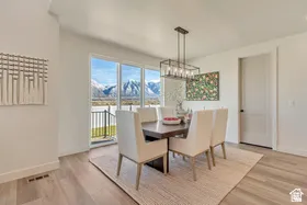 Dining area featuring expansive sliding glass doors, light wood-finish flooring, and a contemporary linear chandelier