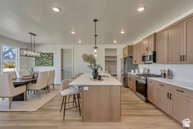 Spacious kitchen with light wood-finish flooring, light-toned cabinetry, and stainless steel appliances