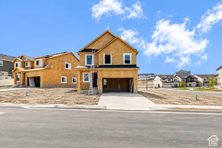 New construction framing with multiple window openings, an attached garage, and a concrete driveway