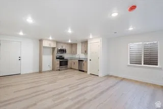 Open-concept living space featuring wood-finish flooring, recessed lighting, and a kitchen with light wood cabinetry