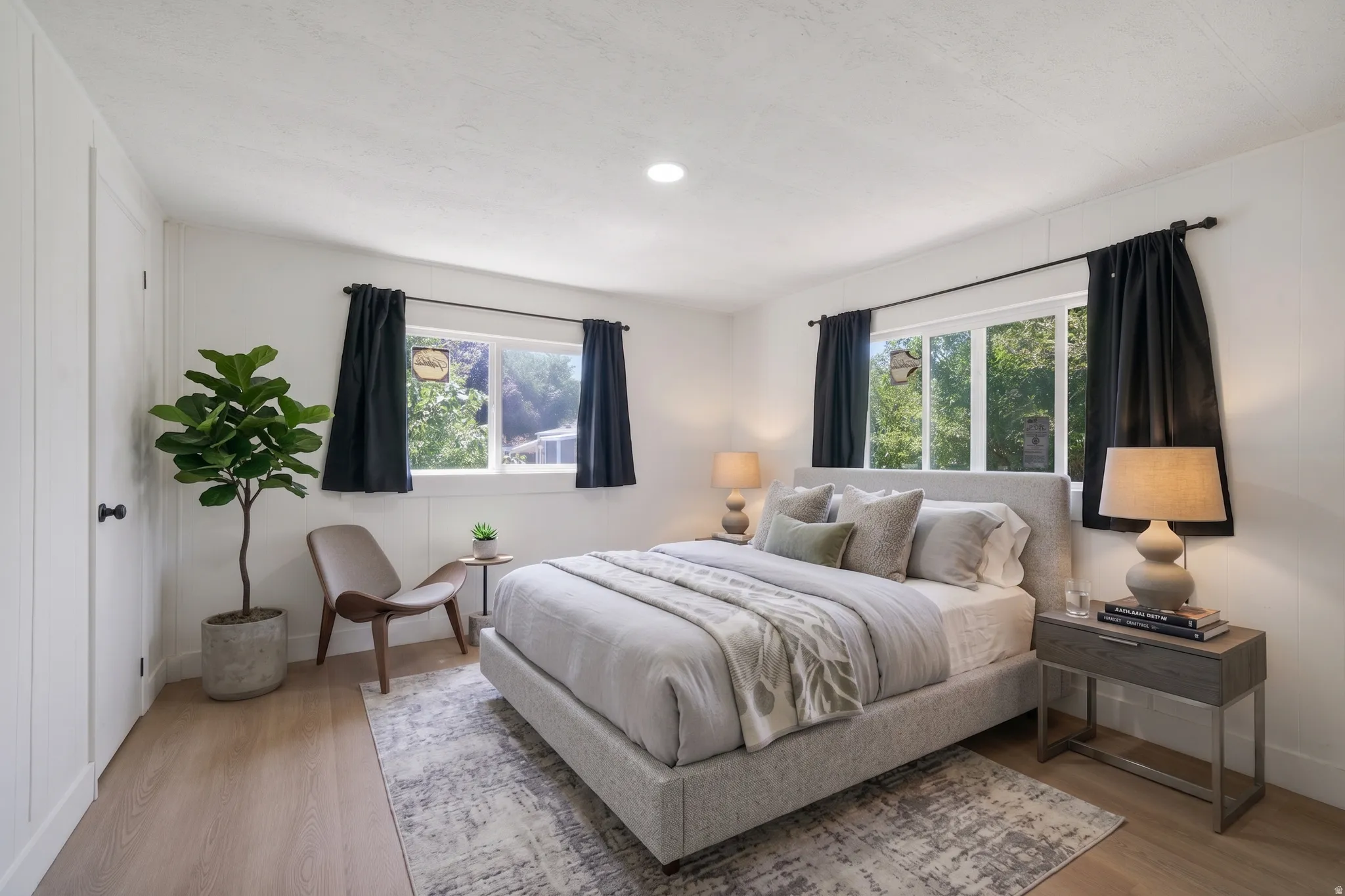 Recessed lighting illuminates this room, featuring light wood-finish flooring and white walls