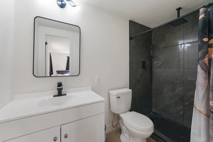 Contemporary bathroom featuring a white vanity with a rectangular undermount sink, matte black faucet, and a sleek black-framed mirror