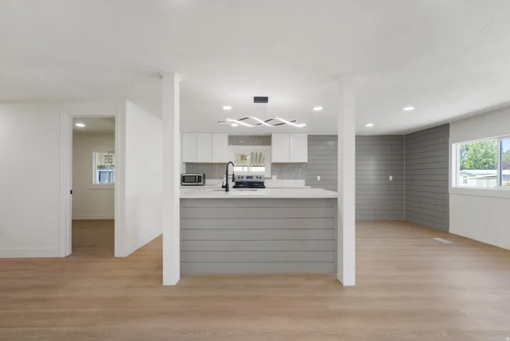 Modern kitchen featuring white cabinetry, a light-toned countertop, and a contemporary light fixture