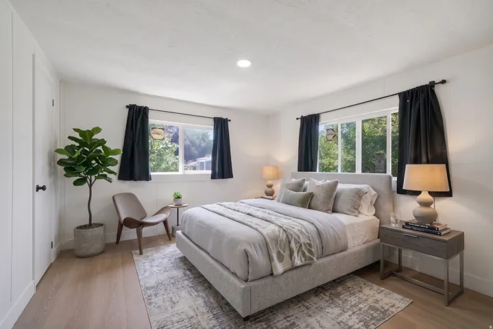 Recessed lighting illuminates this room, featuring light wood-finish flooring and white walls