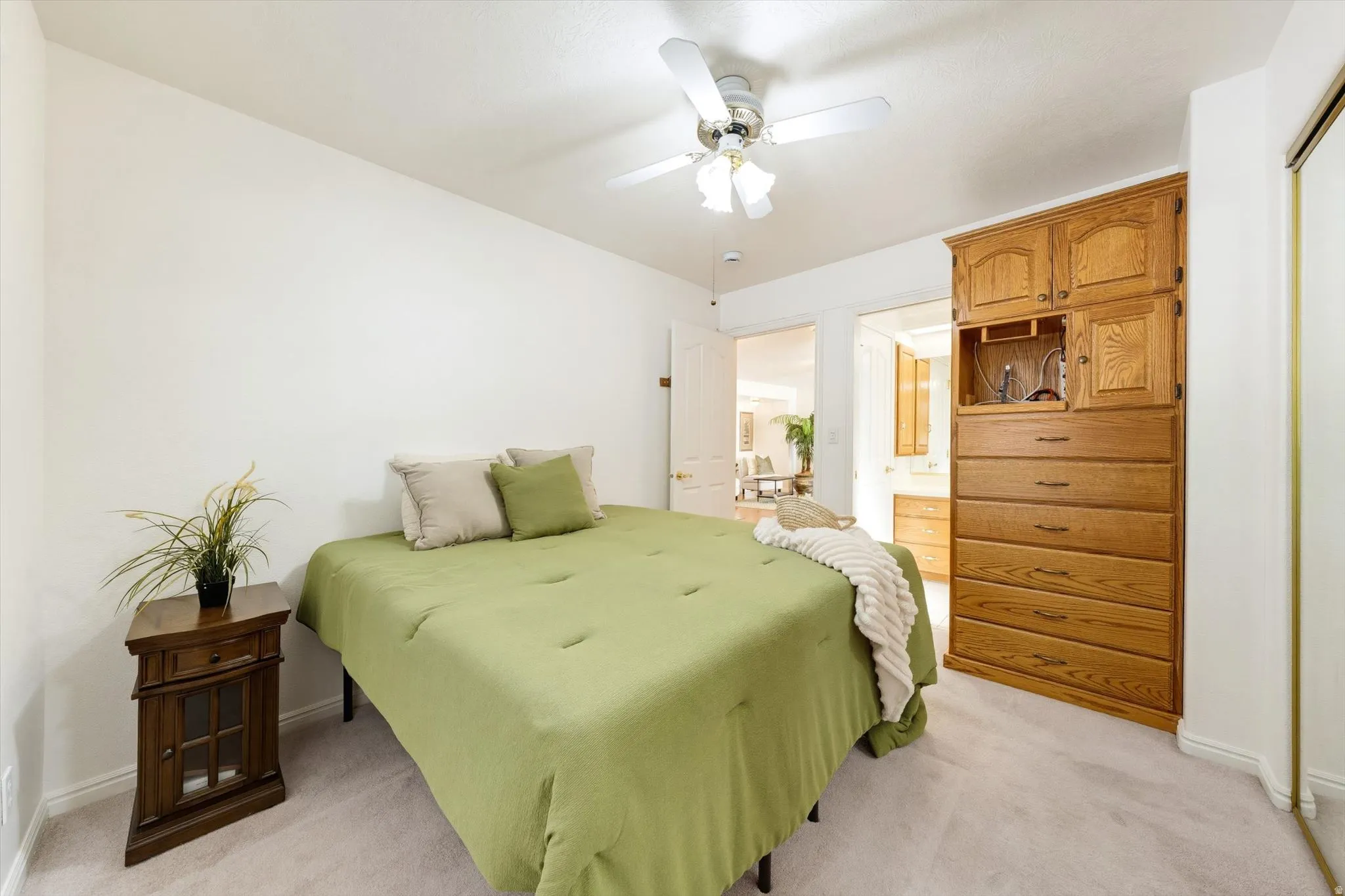 Built-in wood-finish cabinetry, neutral carpeting, and a ceiling fan with integrated lighting