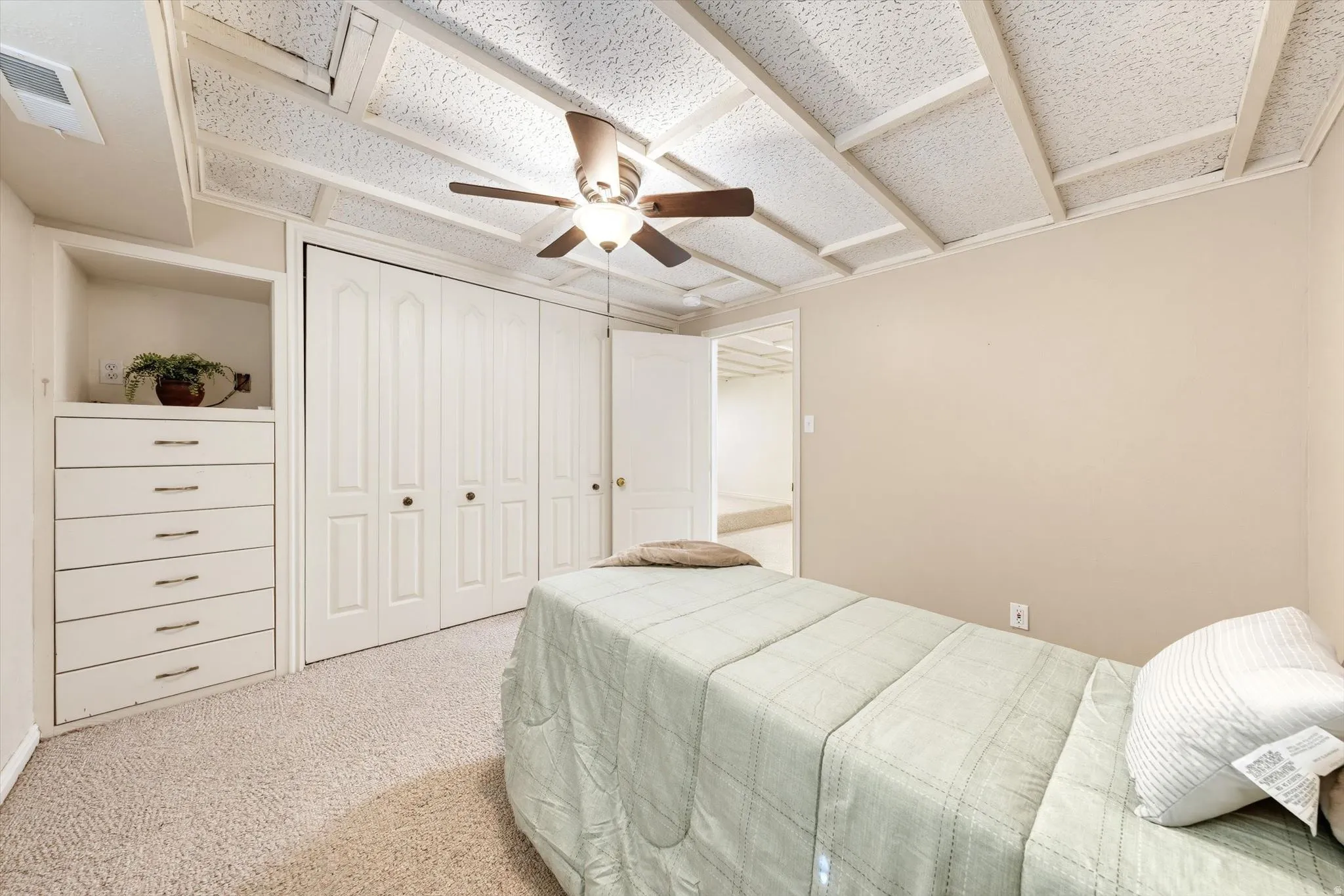 Built-in dresser with six drawers, carpet flooring, ceiling fan, and bi-fold closet doors
