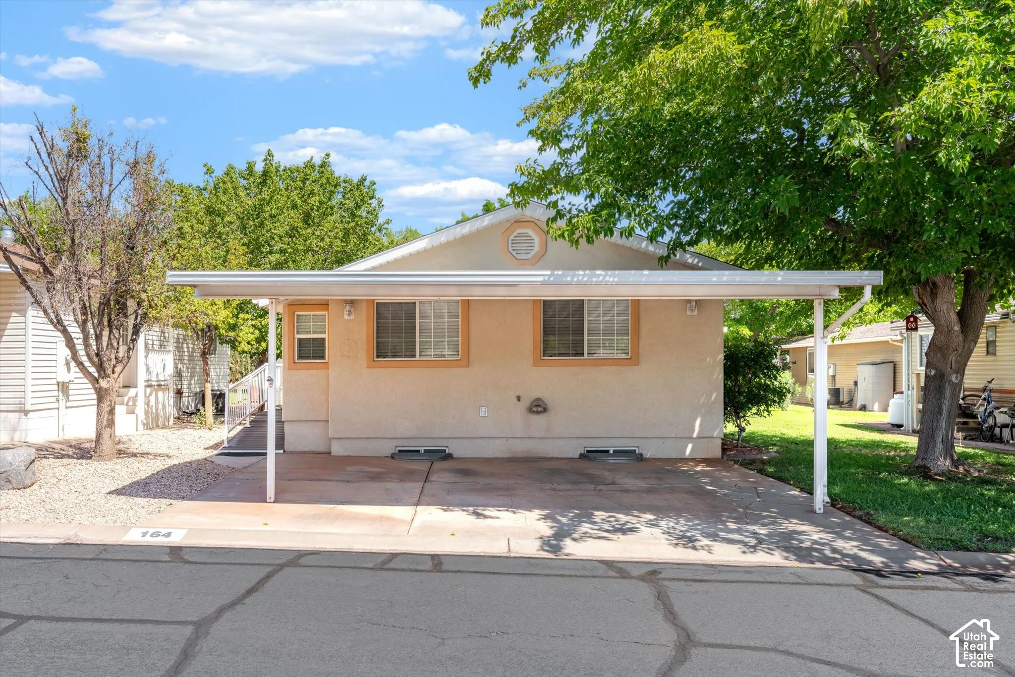 Single-story exterior with a covered carport, stucco finish, and multiple windows