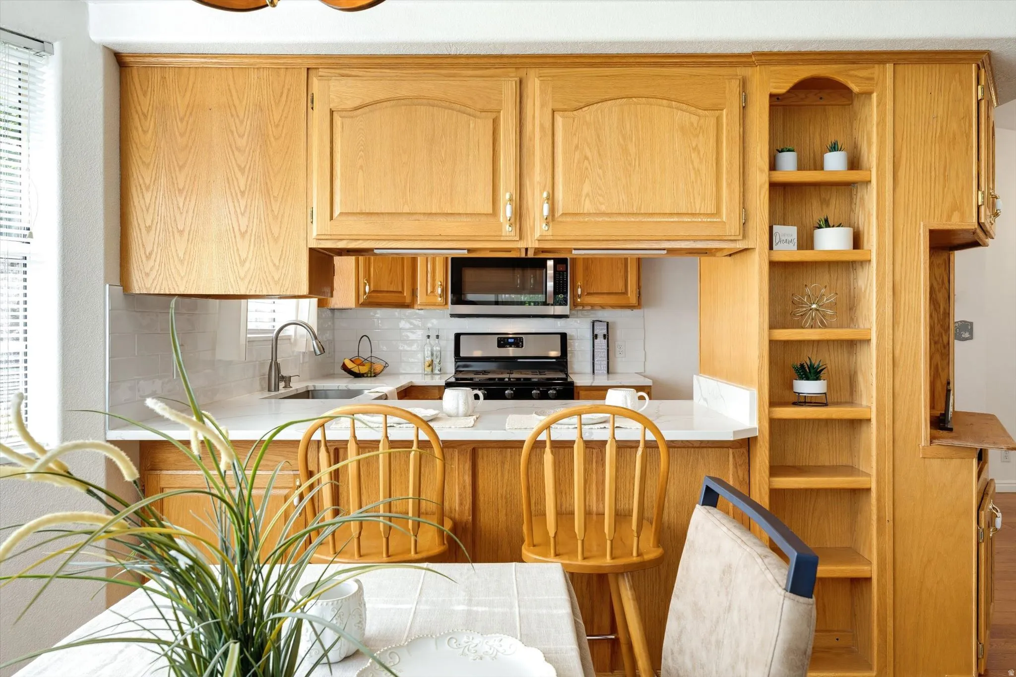 Kitchen featuring wood cabinetry, white countertops, tile backsplash, and built-in shelving