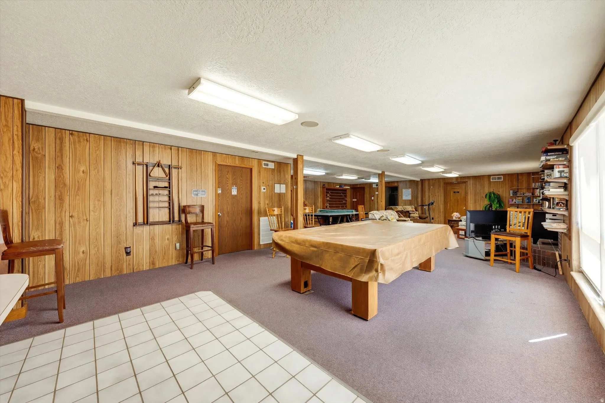 Spacious room featuring wood-finish wall paneling, a large window, and recessed lighting