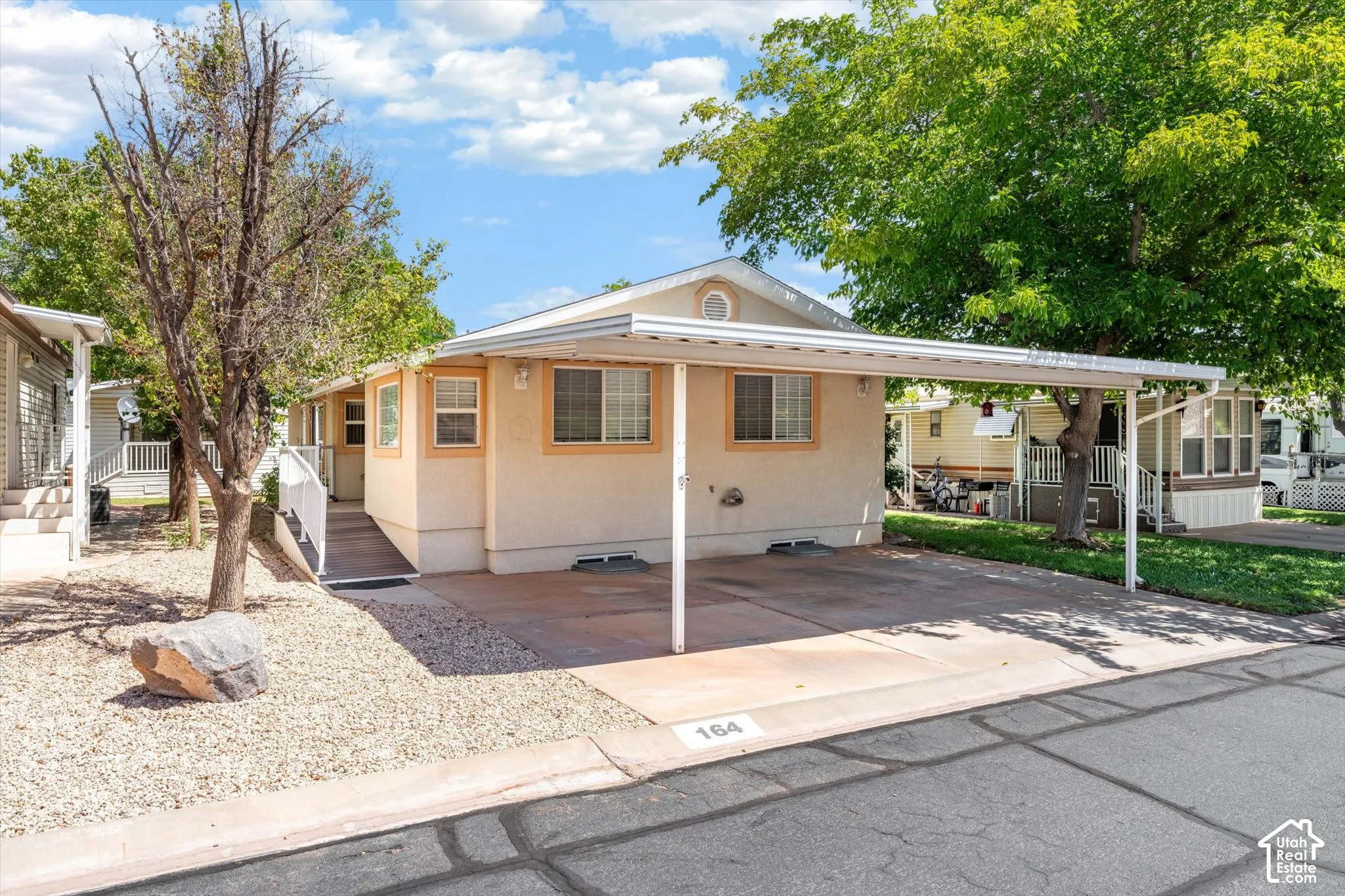 Front exterior with a covered carport, light-toned siding, white trim, and a concrete driveway