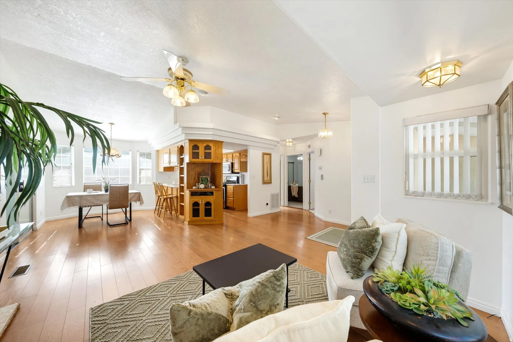 Expansive living area with wood-finish flooring, vaulted ceiling, and recessed lighting
