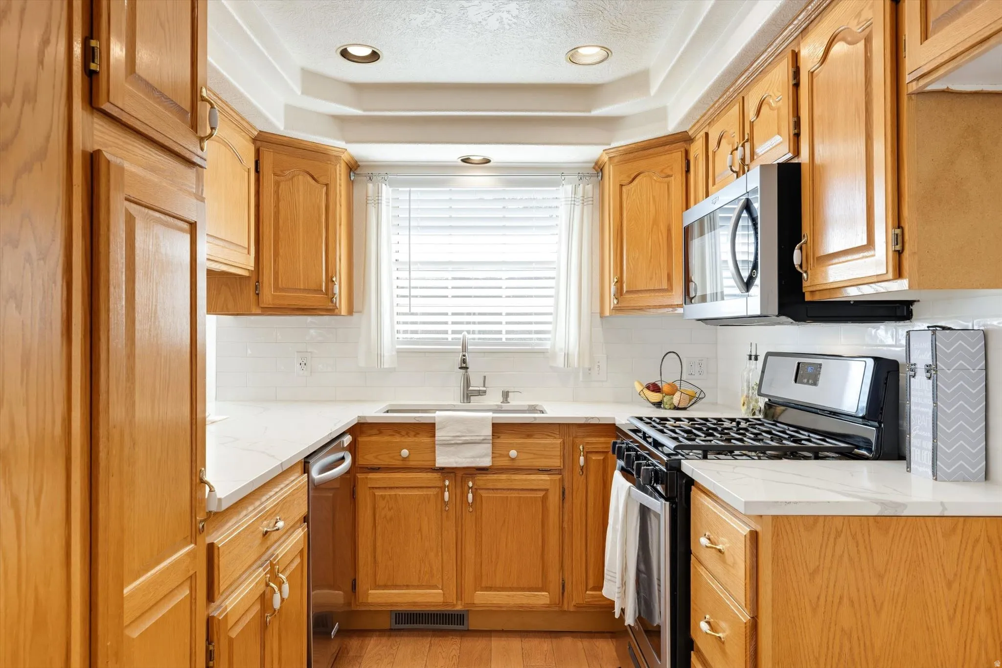 Kitchen featuring wood cabinetry, white countertops, subway tile backsplash, stainless steel appliances, and recessed lighting