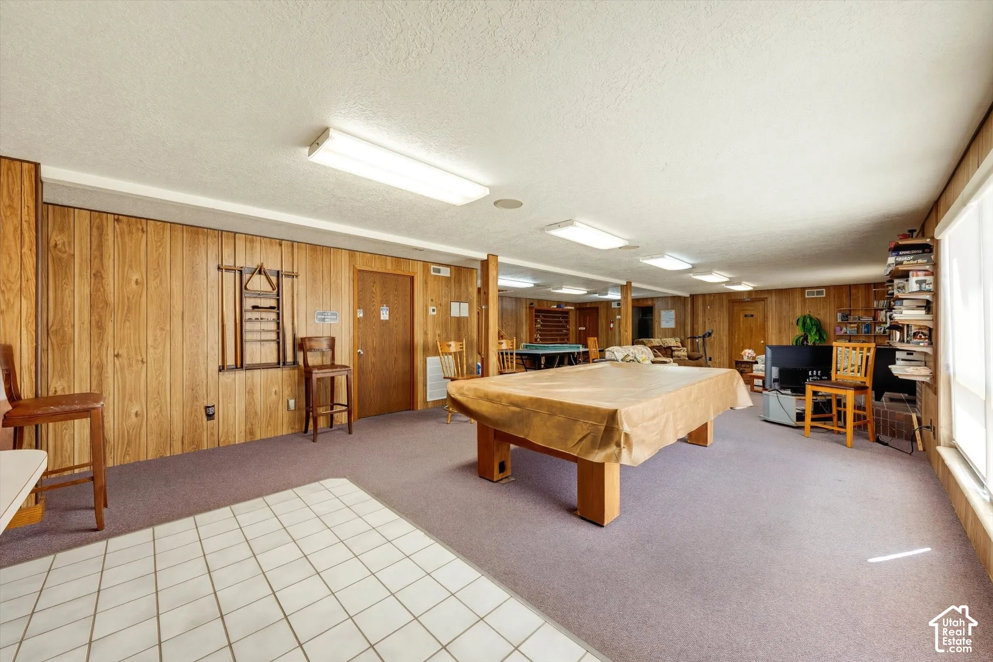 Spacious room featuring wood-finish wall paneling, a large window, and recessed lighting