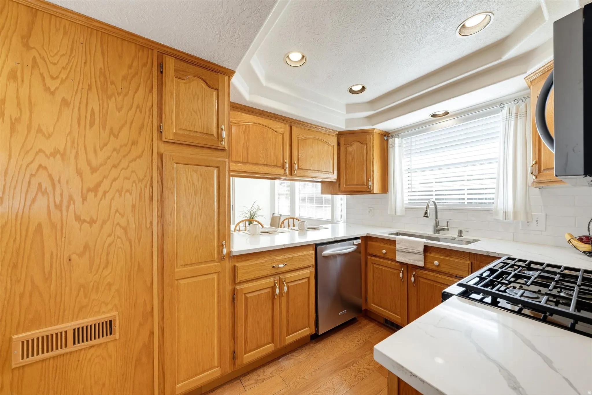 Kitchen featuring wood-finish cabinetry, white countertops, stainless steel appliances, a white subway tile backsplash, and recessed lighting