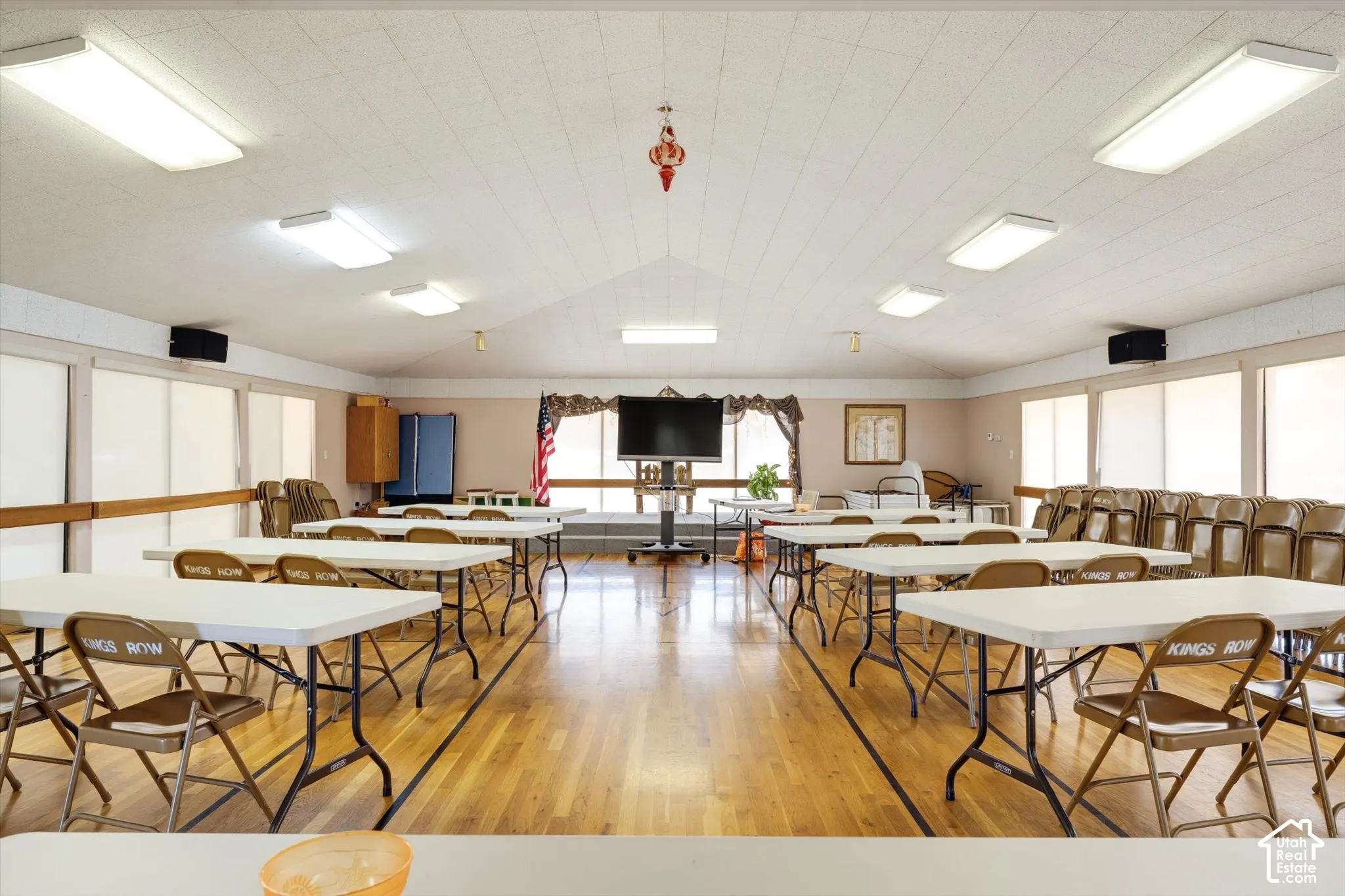 Vaulted ceiling with recessed lighting, wood-finish flooring, and multiple window panels