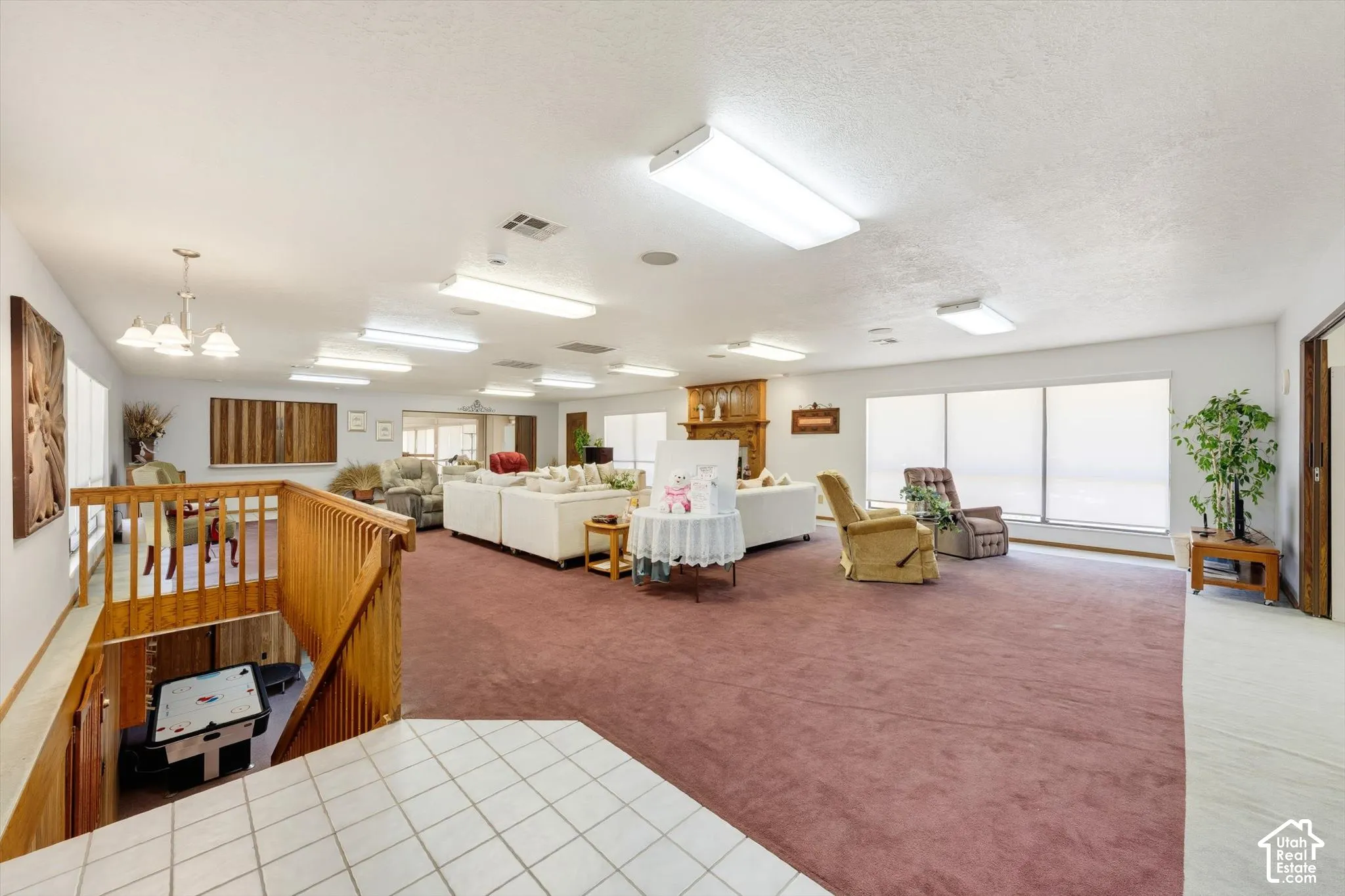 Expansive interior with carpeted flooring, multiple windows, a wood-finish staircase, and built-in overhead lighting