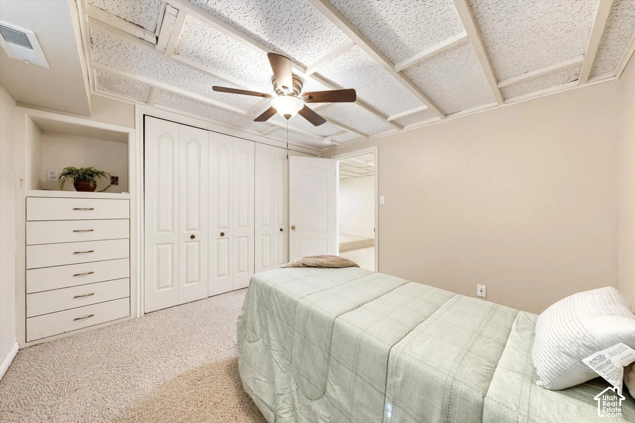 Built-in dresser with six drawers, carpet flooring, ceiling fan, and bi-fold closet doors
