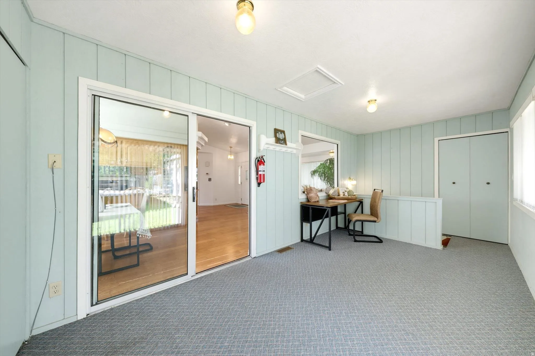 Sliding glass door entry, ceiling-mounted light fixtures, built-in closet, and light-toned wall paneling