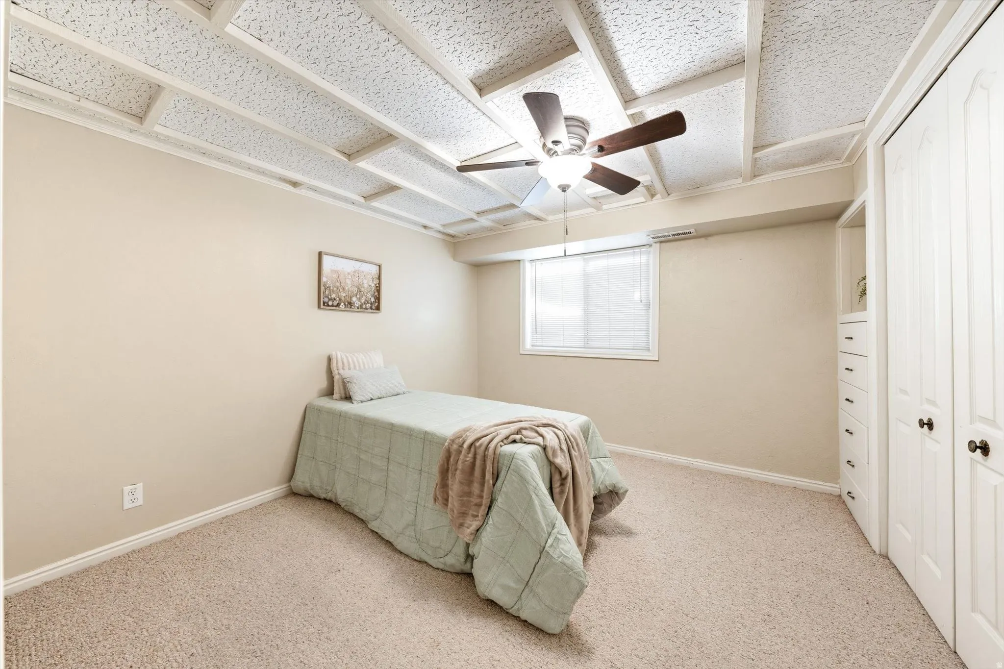 Carpeted room featuring a ceiling fan, recessed window, and built-in closet with drawers