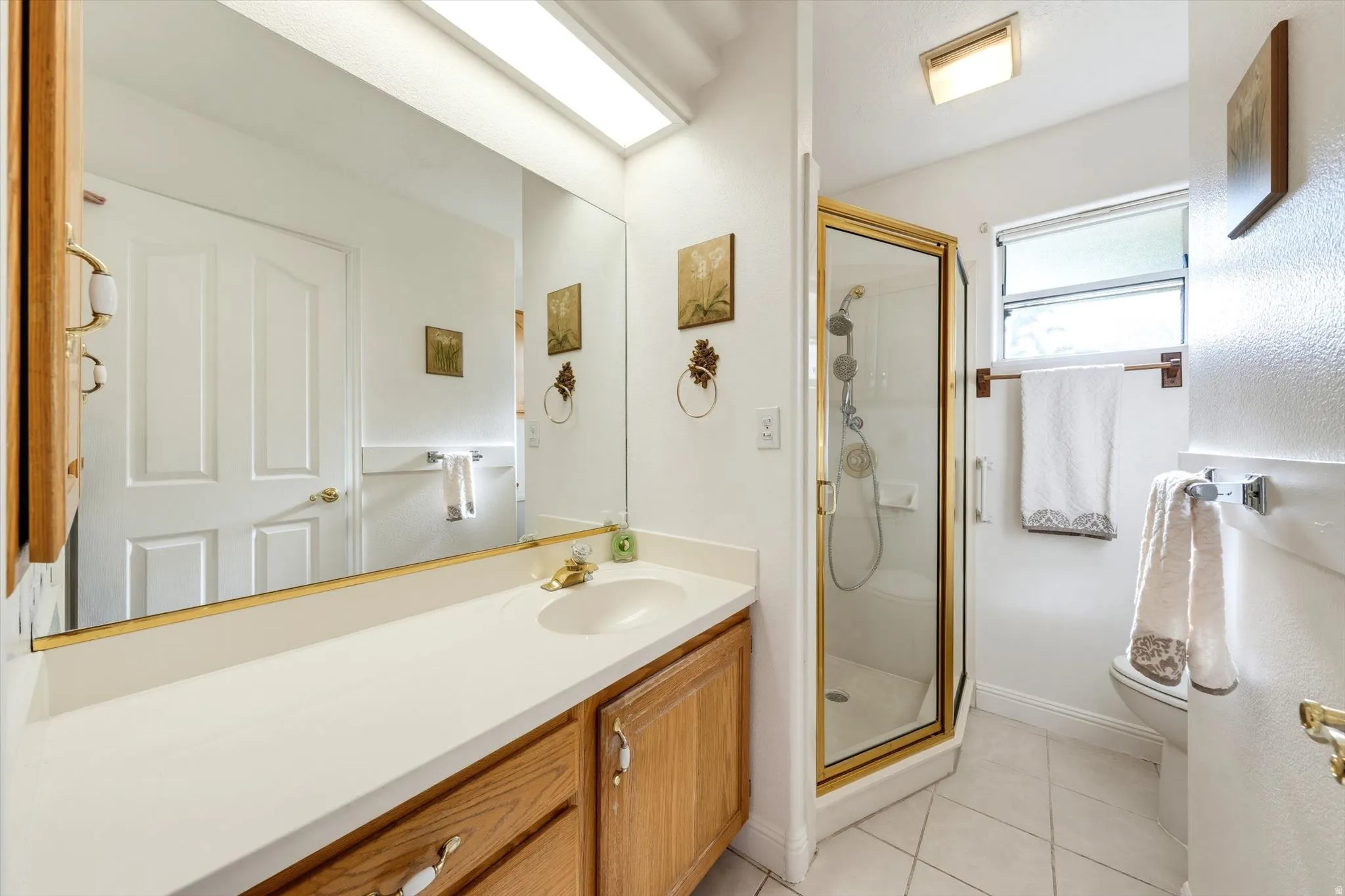 Bathroom featuring a single vanity with wood-finish cabinetry, a white countertop, and an integrated sink