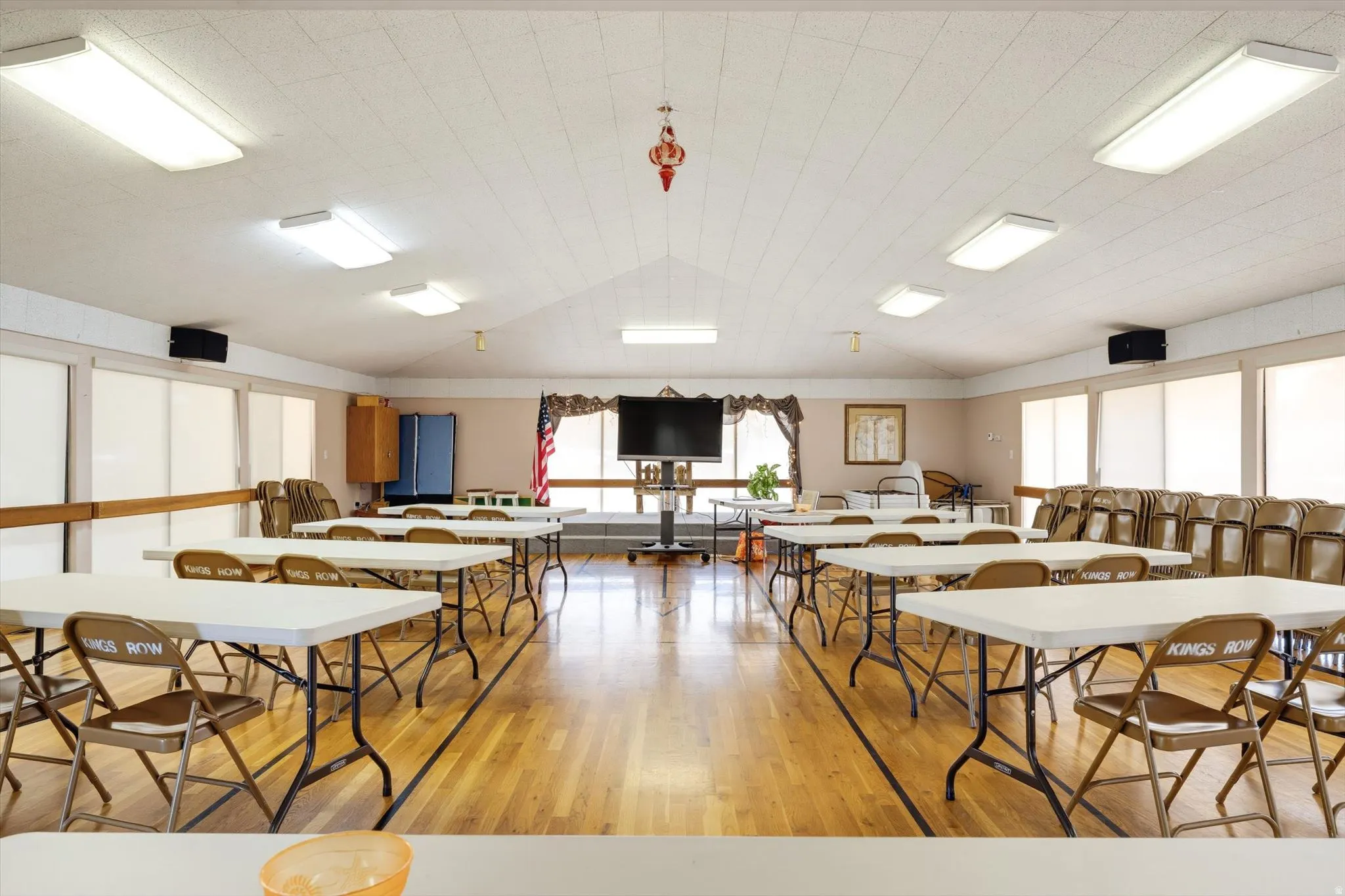 Vaulted ceiling with recessed lighting, wood-finish flooring, and multiple window panels