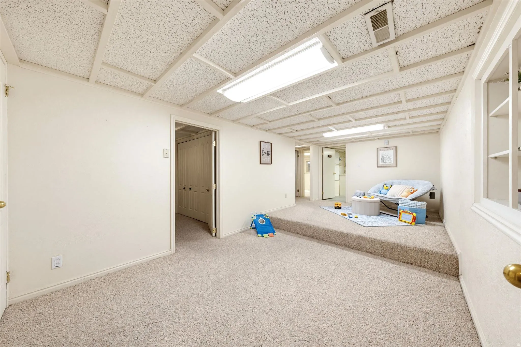 Carpeted flooring, acoustic tile ceiling, recessed lighting, built-in shelving, and a bi-fold closet door