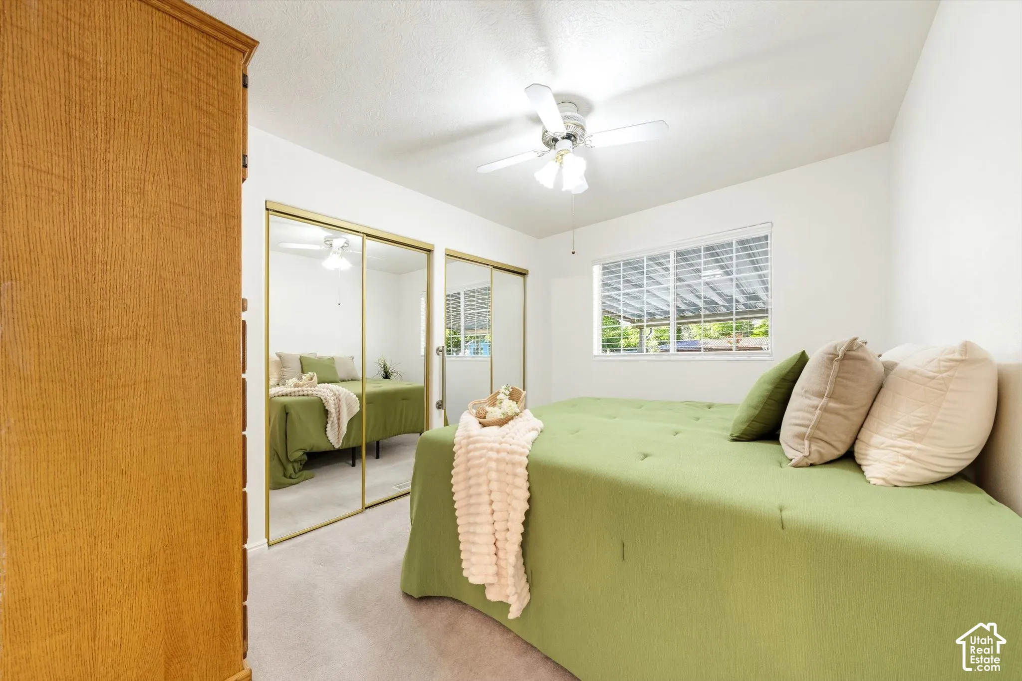 Integrated ceiling fan, neutral wall color, window with horizontal blinds, mirrored closet doors, and light-colored carpeting