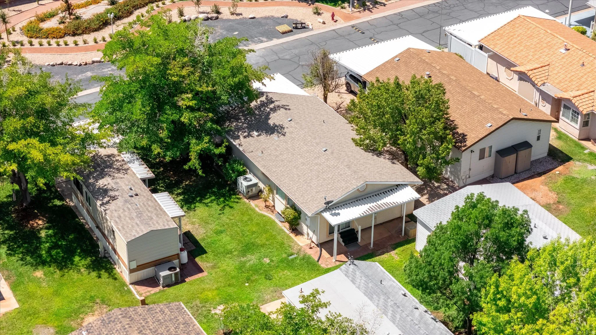 Rear exterior featuring a covered patio with a pergola, mature trees, and a grassy yard