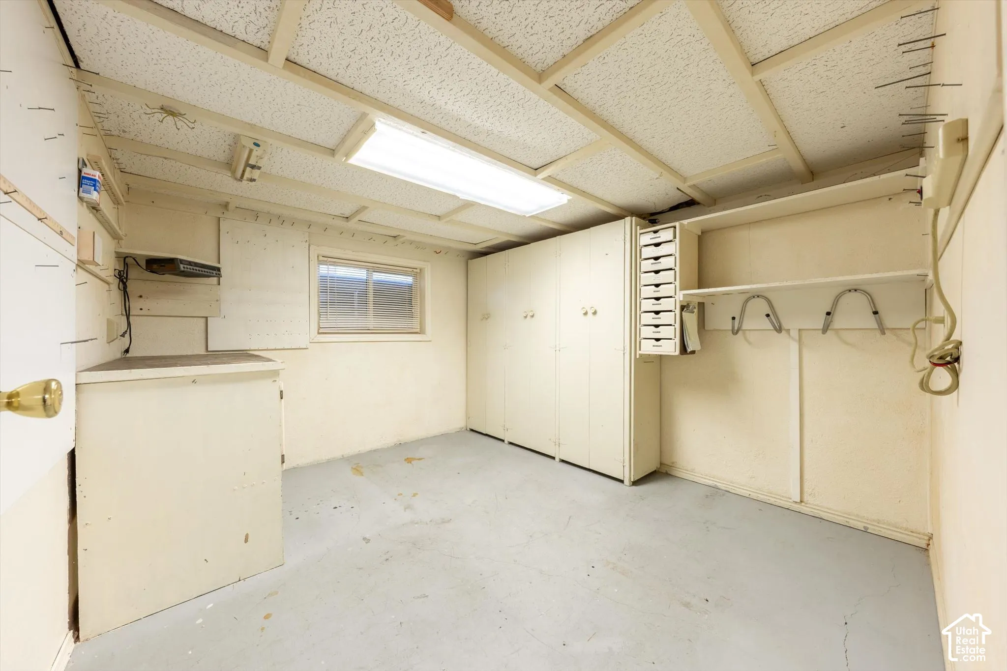 Window-equipped utility space featuring built-in cabinetry, shelving, and a drop-ceiling