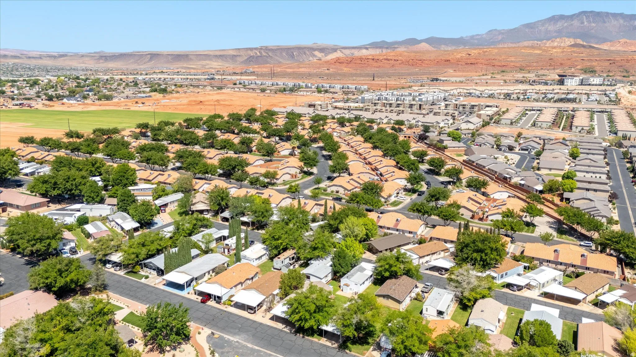 Community setting featuring residential homes with mature tree landscaping, paved streets, and a mountainous backdrop