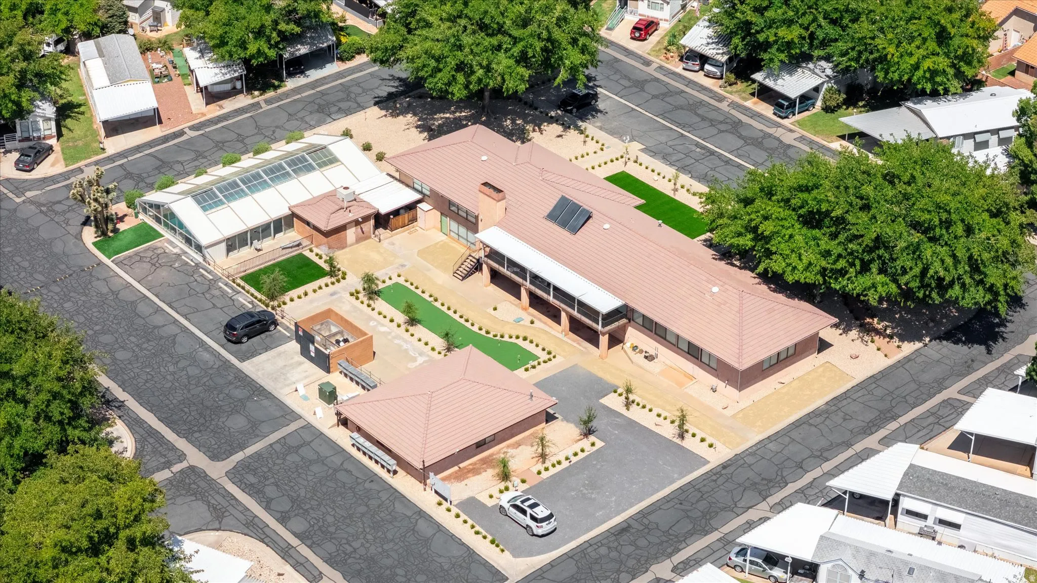 Expansive property featuring a large main residence, a separate auxiliary structure, and a glass-enclosed structure with solar panels