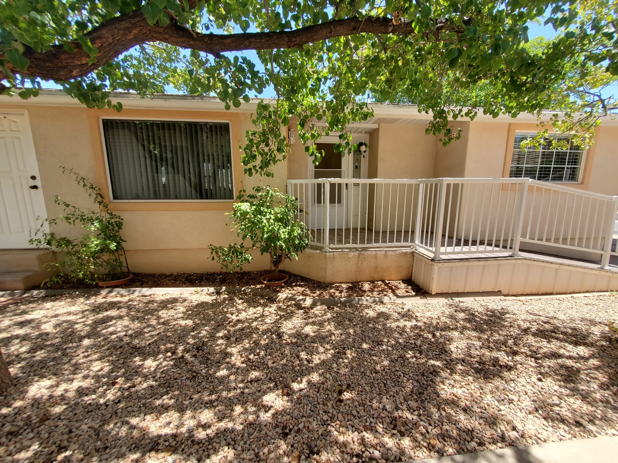 Exterior facade featuring a covered entry porch, white railings, and a ramp for accessibility