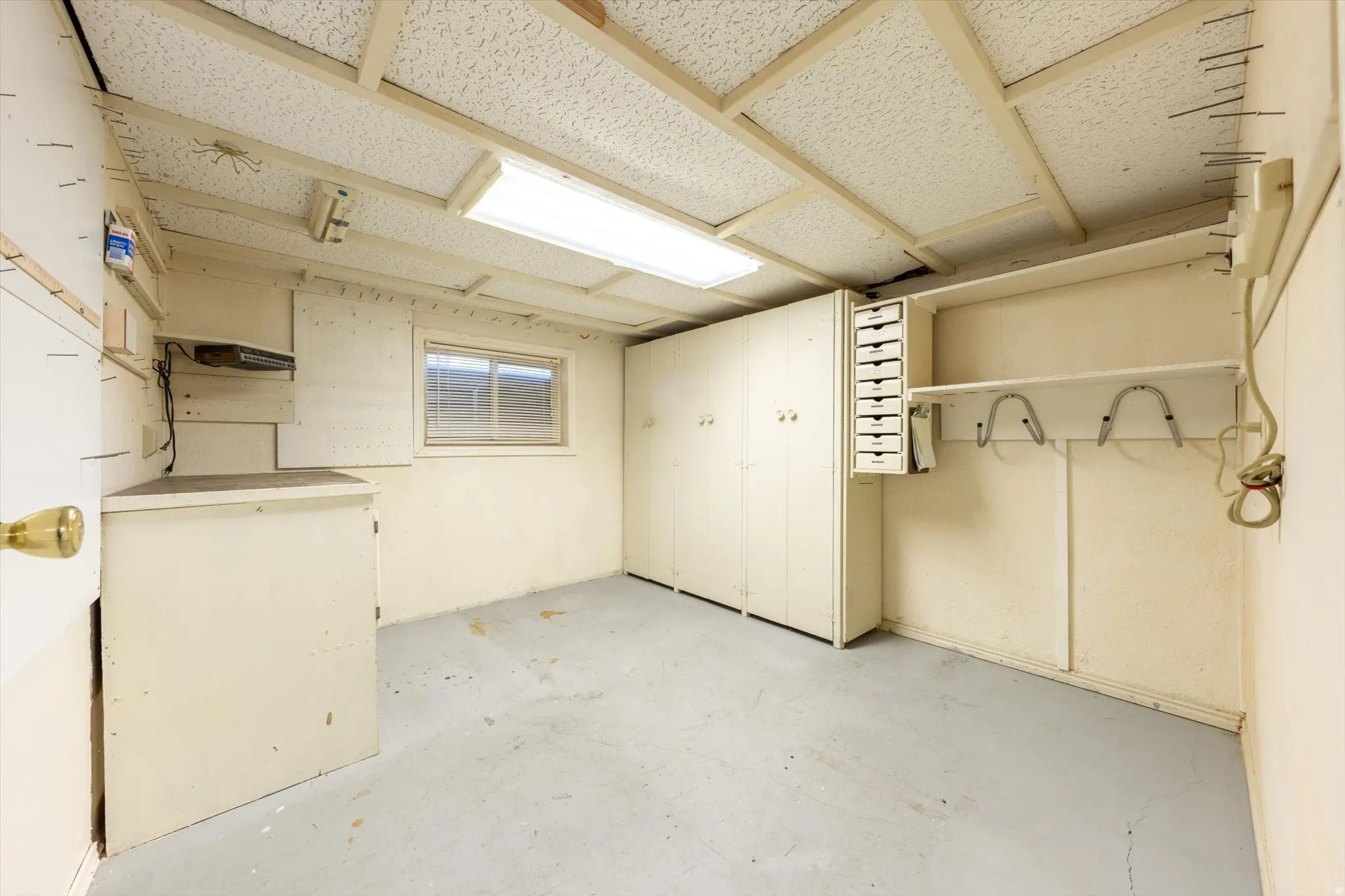 Window-equipped utility space featuring built-in cabinetry, shelving, and a drop-ceiling