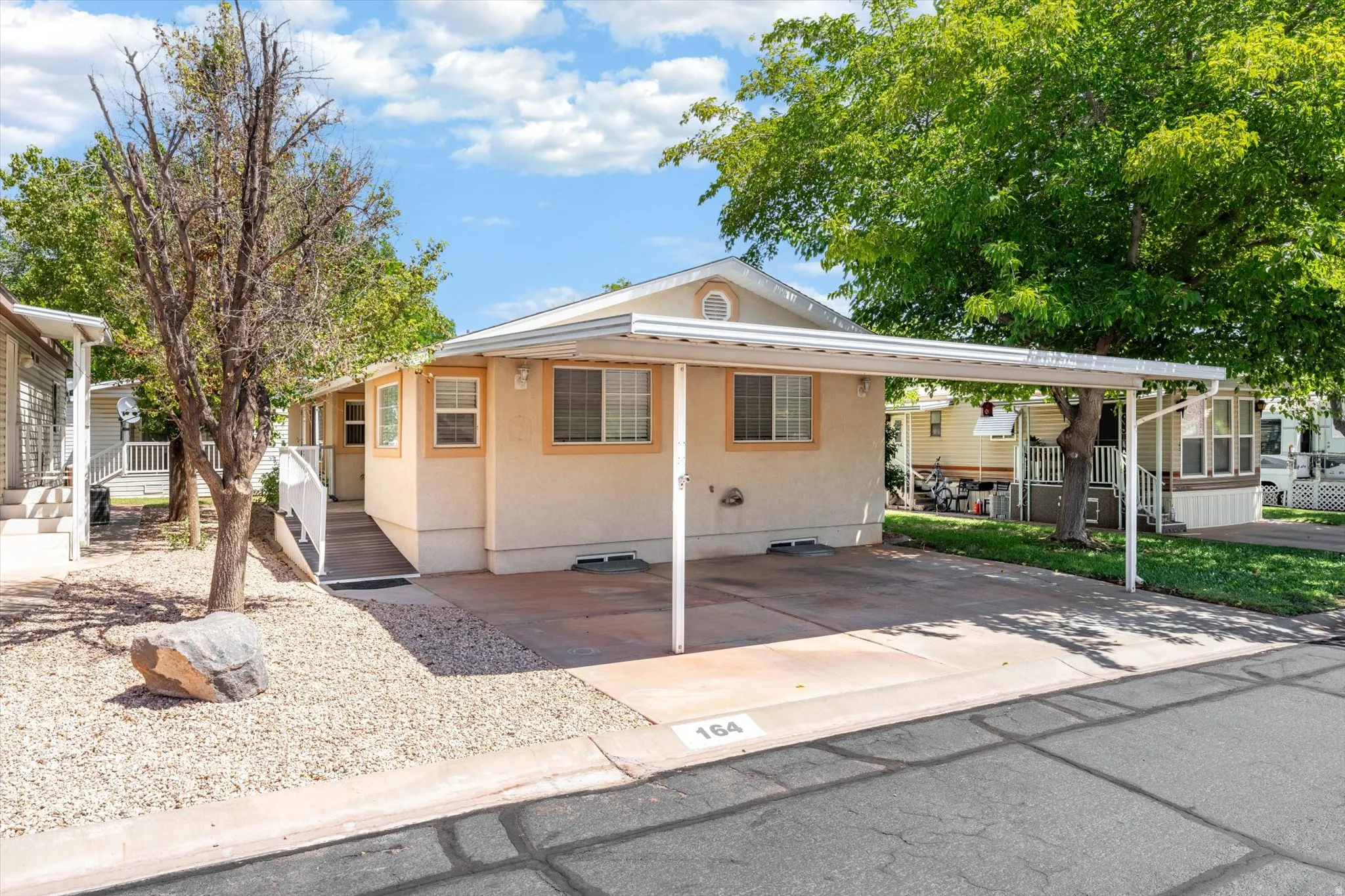 Front exterior with a covered carport, light-toned siding, white trim, and a concrete driveway