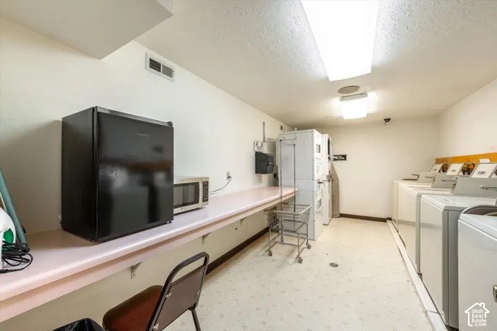 Laundry facility featuring multiple washer and dryer units, a utility counter, and overhead lighting