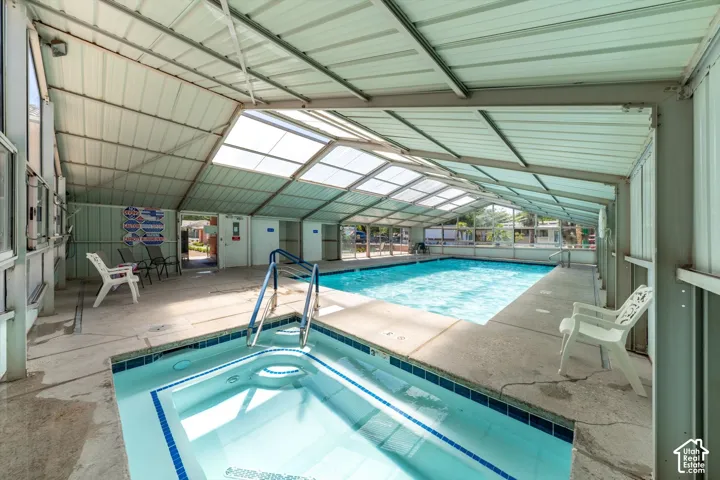 Enclosed indoor swimming pool with a connected spa, featuring a translucent roof and side panels