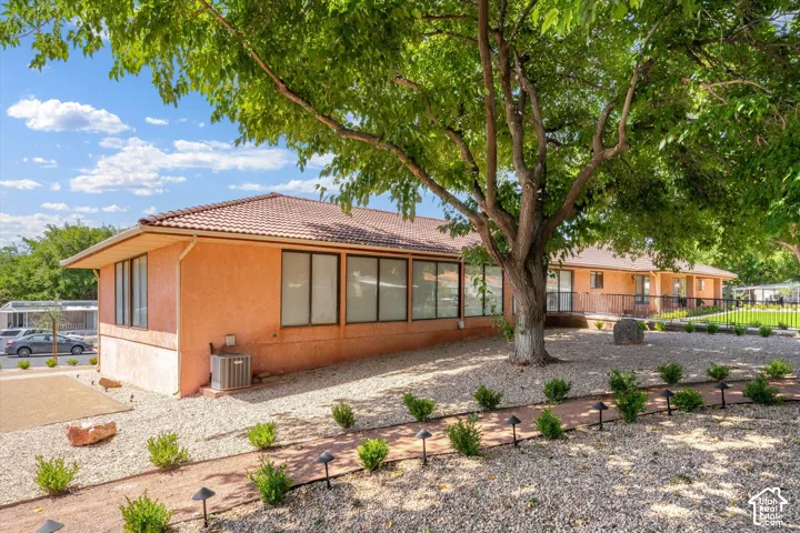 Terracotta tile roof, stucco exterior, large windows, mature trees, and landscaped gravel beds