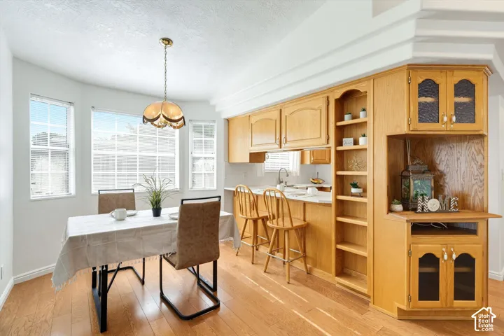 Hardwood-finish flooring, built-in wooden cabinetry, recessed shelving, and a bay window dining area with an attached pendant light fixture