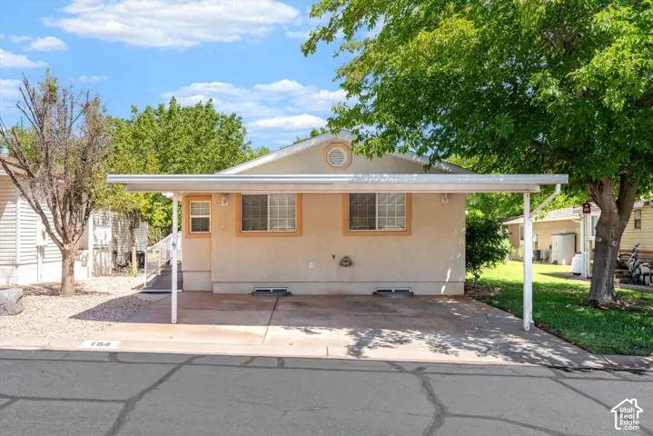 Single-story exterior with a covered carport, stucco finish, and multiple windows
