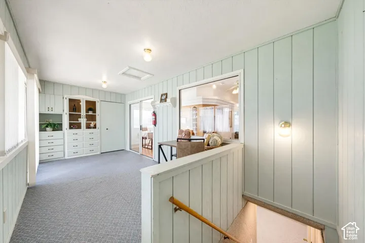 Built-in cabinetry with glass display doors, sliding glass door, overhead lighting, wall sconce, and wood-finish handrail