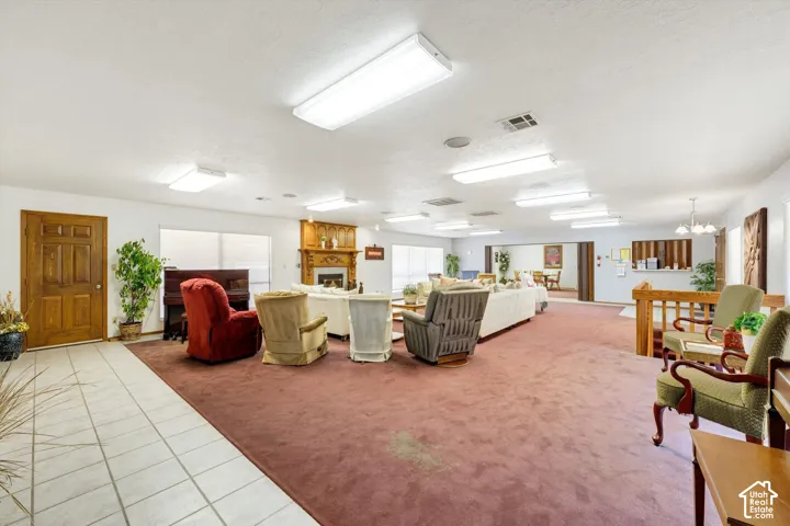 Spacious living area featuring extensive carpeting, a wood-finish entry door, and multiple ceiling-mounted light fixtures