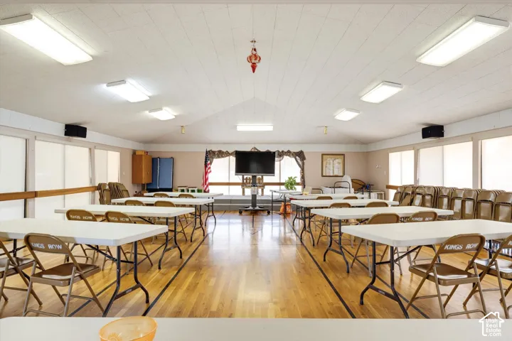 Vaulted ceiling with recessed lighting, wood-finish flooring, and multiple window panels