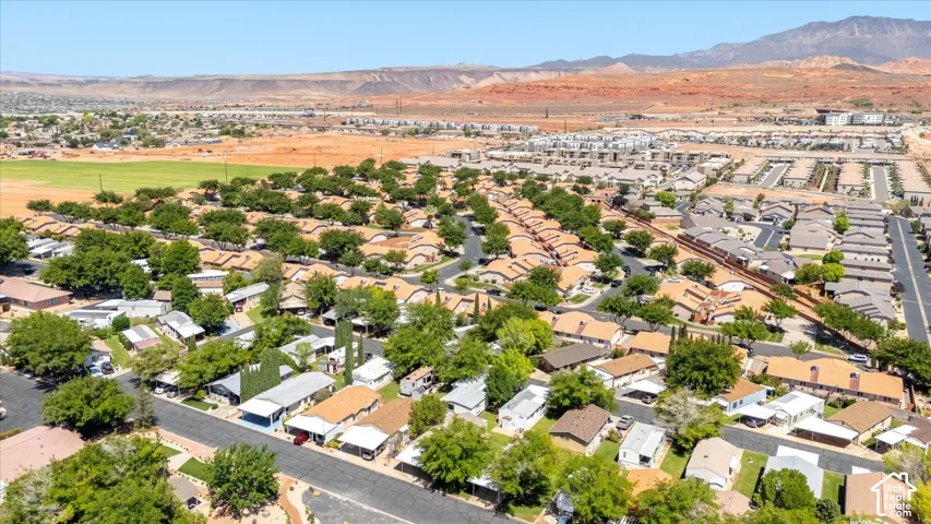 Community setting featuring residential homes with mature tree landscaping, paved streets, and a mountainous backdrop