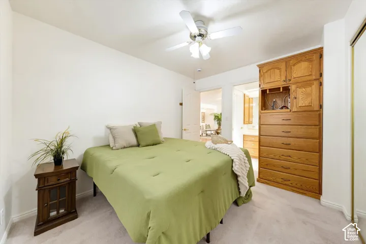 Built-in wood-finish cabinetry, neutral carpeting, and a ceiling fan with integrated lighting